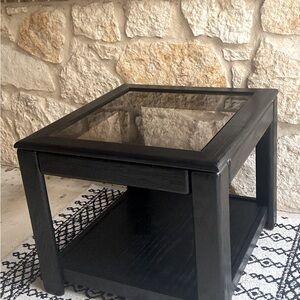 Cute black side table with tinted glass top. Approx 2’ by 2’ and 21” tall.
